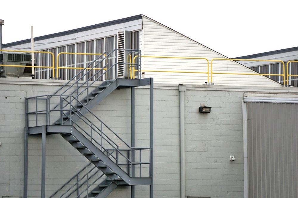 Escalera metálica exterior con barandilla en una nave industrial